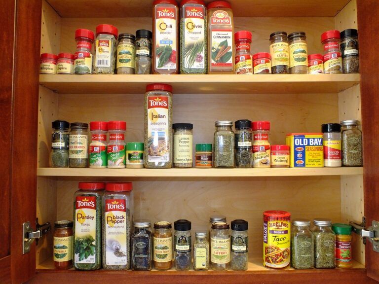 Spice jars neatly organized in a wooden kitchen cabinet, showcasing a clutter-free storage solution for small kitchens